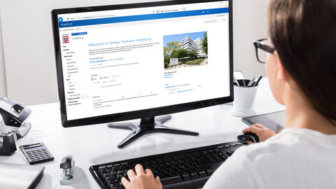 Junge Frau, die auf ihrem PC mit SharePoint arbeitet