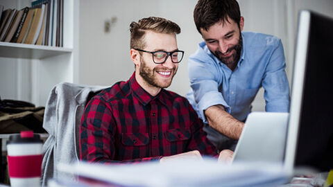 Mann, der einem möglichen Trainee etwas am Computer erklärt