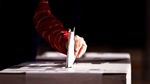 Hand an der Wahlurne bei der Stimmzettel-Abgabe