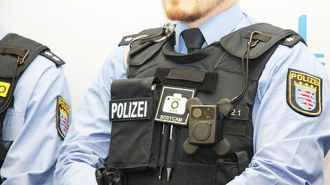 Taktische Überziehweste der Polizei, an deren rechter Seite eine verkabelte Bodycam hängt