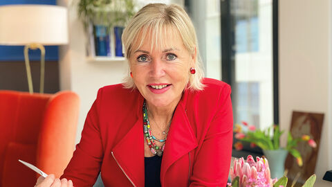 Prof. Dr. Kristina Sinemus, die einen roten Blazer trägt, in ihrem Homeoffice