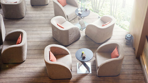 Blick von oben auf einladenden Lounge-Bereich mit locker gruppierten hellen Sesseln und Beistelltischen