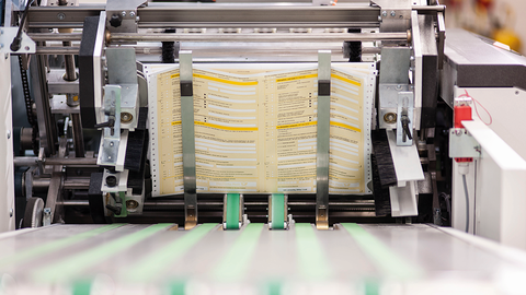 Antragsformulare, die im Ausgabefach der HZD-Druckmaschine liegen