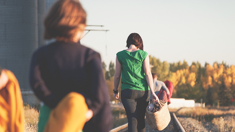 Rückenansicht von Frauen mit leichtem Gepäck, die an einem Bahngleis entlang laufen