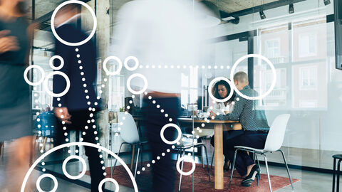 Zwei Frauen am Besprechungstisch mit darübergelegter Grafik aus Kreisen und Punkten, die ganzheitliches Projektmanagement symbolisiert