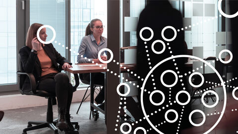 Zwei Frauen am Besprechungstisch mit darübergelegter Grafik aus Kreisen und Punkten, die ganzheitliches Projektmanagement symbolisiert