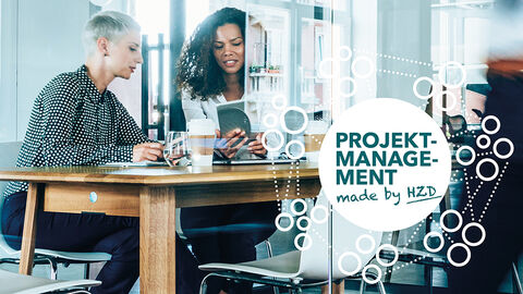 Blick in einen gläsernen Konferenzraum mit drei Frauen im Gespräch, darübergelegt eine Grafik mit dem Schriftzug „Projektmanagement made by HZD“