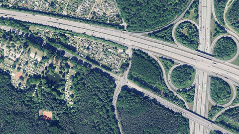 Offene Geodaten für alle - dank der Open-Data-Plattform „Geodaten online“ Luftaufnahme eines Autobahnkreuzes am Rand einer von Wald umgebenen Siedlung