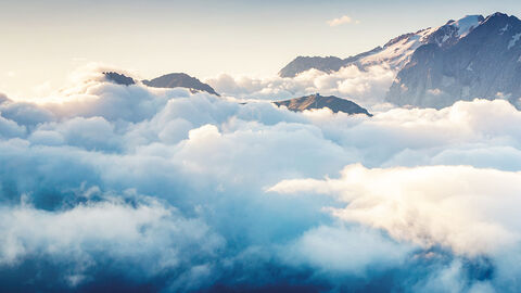 Schroffe Bergkämme, die aus einem Wolkenmeer herausragen