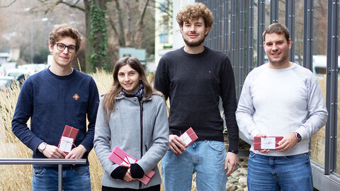Gruppenaufnahme vor dem HZD-Neubau mit vier der fünf Studierenden, die ihre berufliche Qualifikation mit einem Bacholor abgeschlossen haben