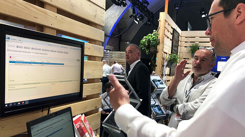 Messestand der HZD mit Präsentation der FISBOX® SBK, die von einem Messebesucher konzentriert verfolgt wird