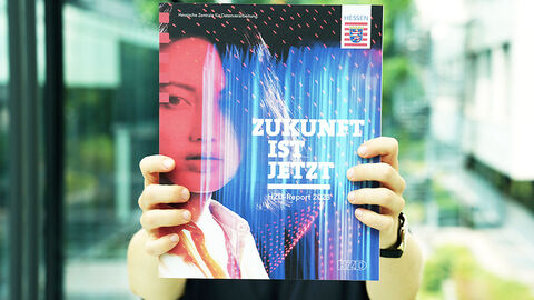 Eine Person hält den HZD-Report 2023 mit ausgestreckten Händen vors Gesicht.