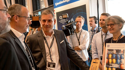 Innenminister Peter Beuth gemeinsam mit Thomas Kaspar, dem Technischen Direktor der HZD, und weiteren Personen am Stand der HZD beim Cybersicherheitsgipfel 2023