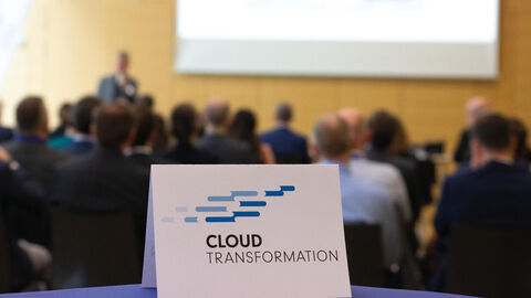 Blick in den Veranstaltungsraum des Kundenforums Programm Cloud-Transformation der HZD mit Aufsteller des Programmlogos im Vordergrund