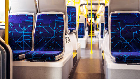 Blick in den leeren Waggon einer U-Bahn mit blau gemusterten Sitzen und gelben Haltestangen