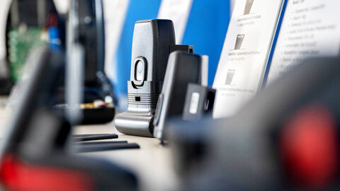 Close-up von Tisch, auf dem eine Fußfessel mit Peripheriegeräten vor einem Bildschirm aufgebaut ist, auf dem die Software zur elektronischen Aufenthaltsüberwachung läuft