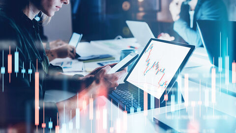 Bildkomposition aus Foto von Frau vor einem Laptop und darüber gelegter Grafik mit farbigen Balken und Zahlenkolonnen