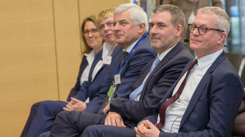 HZD-Direktor Joachim Kaiser sitzt in der ersten Reihe eines Veranstaltungsraums neben anderen VIPs der Landesverwaltung.