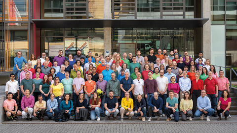 Gruppenfoto von ca. 50-80 Leuten in bunter Kleidung vor dem HZD-Gebäude.