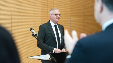 HZD-Direktor Joachim Kaiser steht an einem Stehpult vor einem applaudierenden Publikum