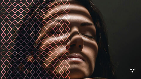 Close-up einer entspannt zurückgelehnten jungen Frau, auf deren Gesicht die durch eine Jalousie gefilterte Sonneneinstrahlung helle Streifen bildet