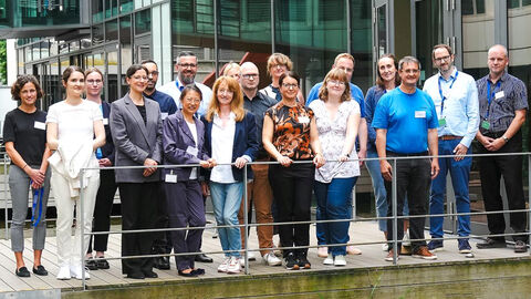 Gruppenfoto der Teilnehmenden an der ALD-Tagung Vergabemanagement, die im Innenhof der HZD entlang einer Metallreling stehen