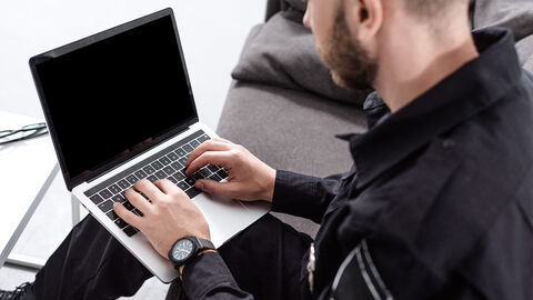 Sitzender Beamter mit dunkler Uniform  und Laptop auf dem Schoß