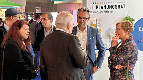 FITKO-Präsident Dr. André Göbel am Messestand des IT-Planungsrats im Gespräch mit einer Gruppe von Menschen