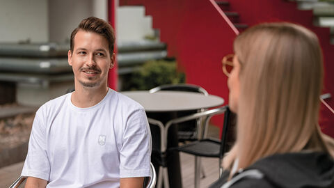 Junger Mann beim Gespräch mit Personalexpertin im Innenhof der HZD