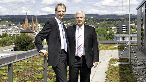 Zwei Männer stehen auf Dachterrasse. Im Hintergrund sieht man Wiesbaden