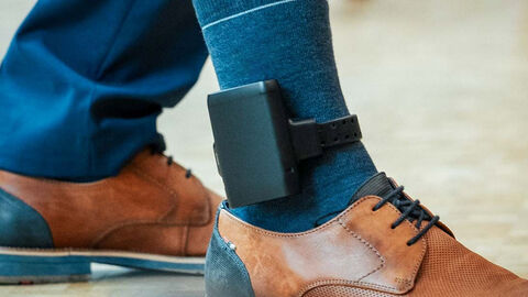 Close-up auf den Knöchel eines Mannes, der das Tätergerät der elektronischen Fußfessel trägt