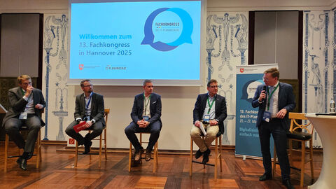 Vier Männer und ein Moderator bei einer Podiums-Diskussion