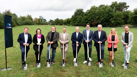 Neun VIPs aus Politik und Wirtschaft auf der grünen Wiese mit Spaten in der Hand